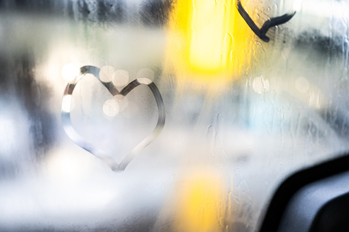 Close-up of heart shape on vehicle glass.