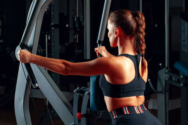 istock Young attractive woman doing exercises for arms in a training machine 1468513837