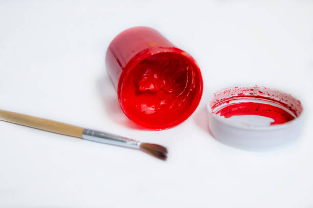 瓶の白いテーブルの上には赤の水彩画があります。赤い水彩画の逆さ缶をブラシで。開いた絵の具が付いた赤い水彩画の瓶。