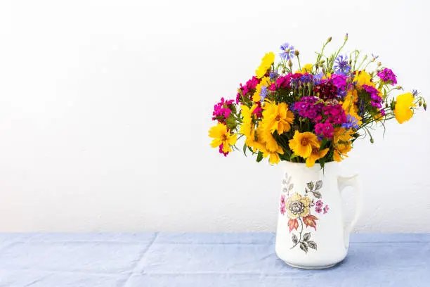 Beautiful summer bouquet of carnations, cornflowers and yellow chamomiles, part of home interior