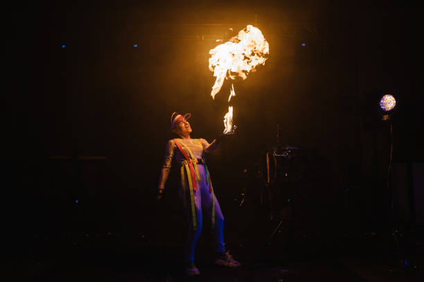 istock Fire show, dancing with flame, master with fireworks, performance indoors, draws a fiery figure in the dark, bright sparks in the night. A woman in a suit LED dances with fire. Fire and smoke. 1468514405