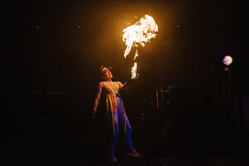 Fire show, dancing with flame, master with fireworks, performance indoors, draws a fiery figure in the dark, bright sparks in the night. A woman in a suit LED dances with fire. Fire and smoke.