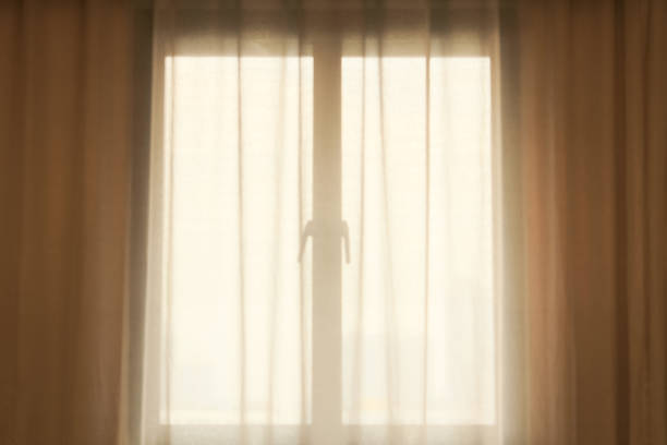 istock Sunlight through window with white curtain. Bright ray of sun shines through window. 1468514997