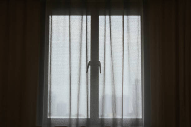 istock Sunlight through window with white curtain. Bright ray of sun shines through window. 1468515093