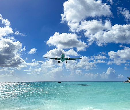 Airplane flying over the beach and ocean to land at airport
