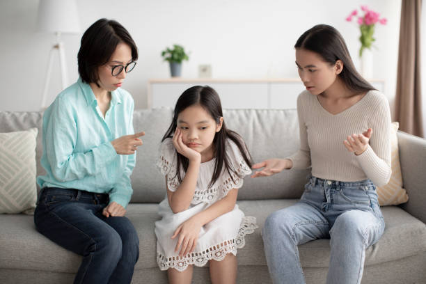 アジアの母親と祖母が家のソファで不幸な少女を叱る - grandmother granddaughter senior adult teenager ストックフォトと画像