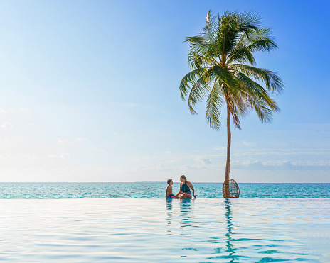 Mother and son At Luxury Resort On Summer Vacation. People Relaxing Together In Edge Swimming Pool Water, Enjoying Beautiful Sea View. Travel. Relationship, Family.