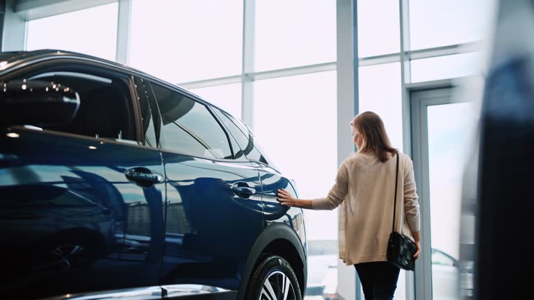 SLO MO Mid adult woman caress a new car with her hand in a car showroom