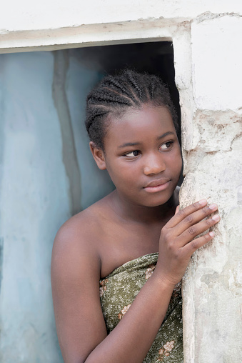Young Afro girl at the door of her house, serious expression, 12 years old, photo