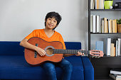 Asian boy portrait in livingroom with guitar.