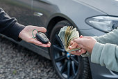 Deal of buying or renting car concept. Hand with car keys, other hand gives money.