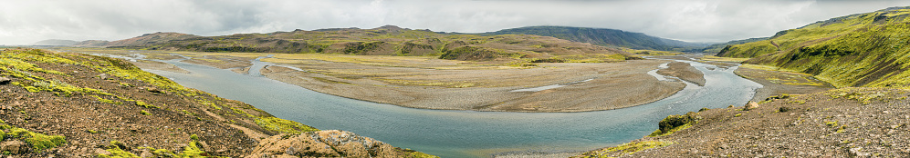 Fossa River valley in Iceland during summer with various creeks running towards the ocean. The vast empty landscape is covered with a dramatic overcast sky.