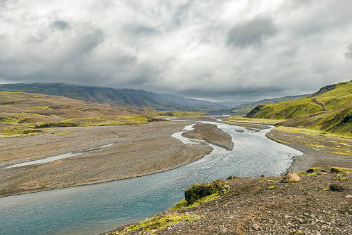 Fossa River valley in Iceland during summer with various creeks running towards the ocean. The vast empty landscape is covered with a dramatic overcast sky.