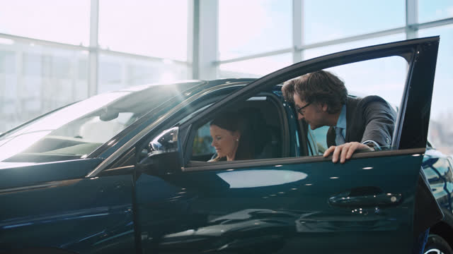 SLO MO Car salesman show car interior to a female customer
