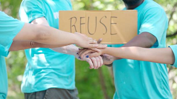 istock Volunteer to help save nature, pick up trash, hold a re-use sign activists starting work with cheering and stacking hands in the circle 1468532042