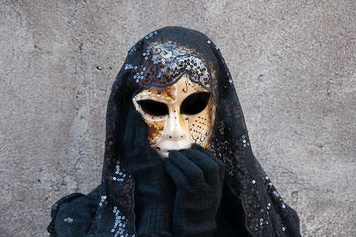 Masked person with gray background in carnival
