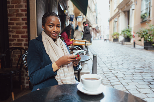 Young african woman using smart phone in a modern cafe close up