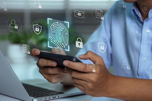 A user accesses document data via a laptop and smartphone equipped with a fingerprint scanner. Cyber security and data protection information privacy internet technology.