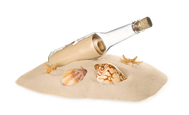 istock Corked glass bottle with rolled paper note and seashells on sand against white background 1468540004