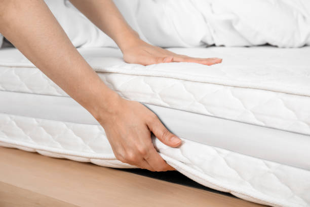 istock Woman touching soft white mattress on bed, closeup 1468540075