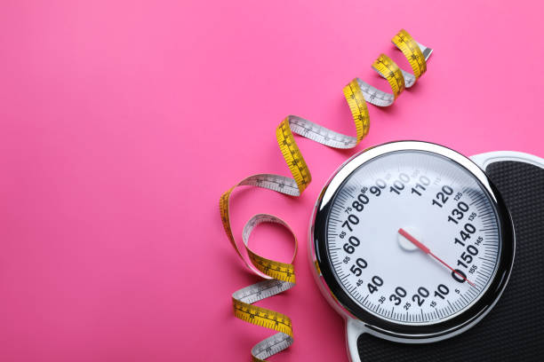 istock Scales and measuring tape on pink background, flat lay. Space for text 1468540280