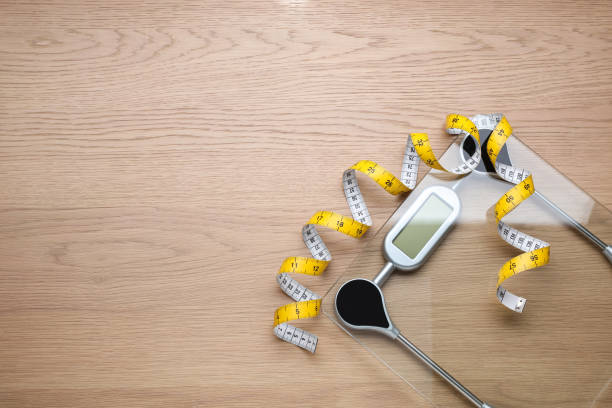 istock Electronic scales and measuring tape on wooden background, flat lay. Space for text 1468540295