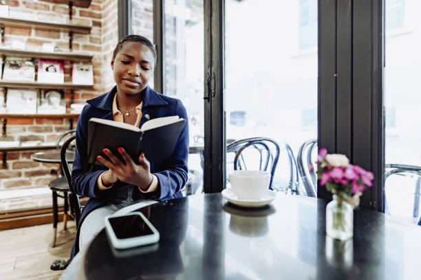 istock Beautiful african girl making notes in diary in cafeteria. 1468540327