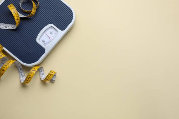 istock Scales and measuring tape on beige background, flat lay. Space for text 1468540375