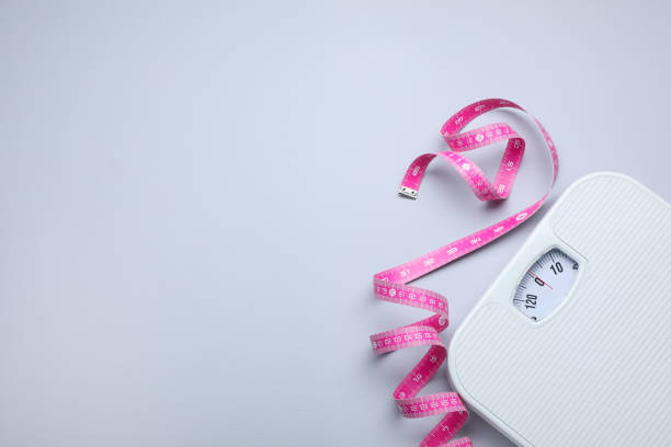 istock Scales and measuring tape on light grey background, flat lay. Space for text 1468540437