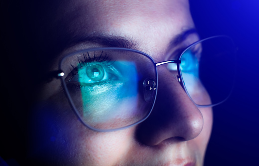 Girl works on internet. Reflection at the glasses from laptop.\nClose up of woman's eyes with black female glasses for working at a computer. Eye protection from blue light and rays.