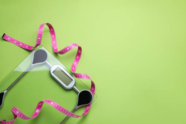 istock Electronic scales and measuring tape on green background, flat lay. Space for text 1468540734