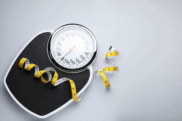 istock Scales and measuring tape on light grey background, top view. Space for text 1468540999