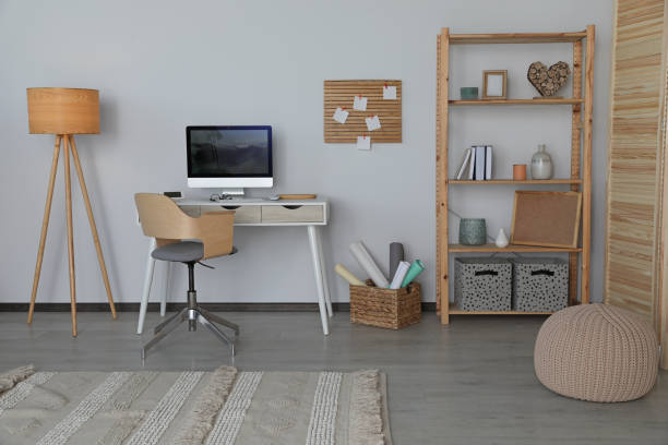 istock Stylish room interior with comfortable workplace and shelving unit near white wall 1468542883