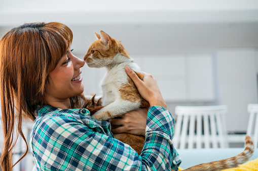 Latina woman age 25-35 is spending time with her cat at home