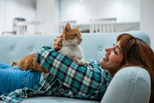 Latina woman age 25-35 is spending time with her cat at home
