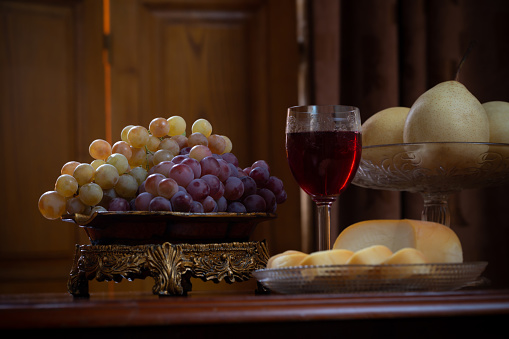 still life with fruits and cheese and glass of red vine on wooden background