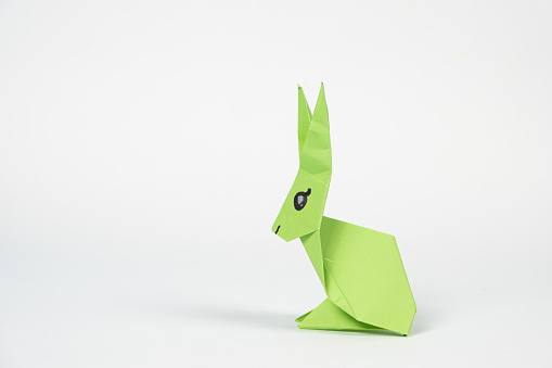 A green origami rabbit on a white background. Crafts for Easter, fold from paper, do it yourself, place for text