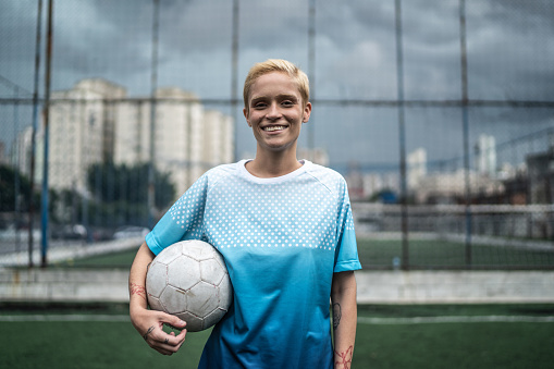 Portrait of a female soccer player holding a soccer ball in the field