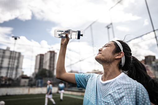 Female soccer player washing face in the field
