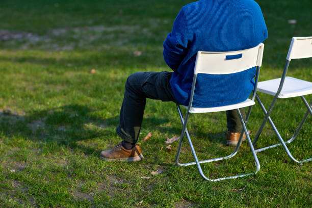 istock A man sits on a white folding chair on the lawn 1468574346