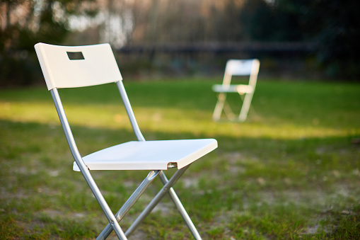 White folding chairs on the lawn outdoors at sunset
