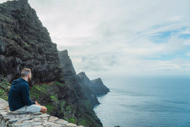istock Man sitting at a viewpoint watching the seascape in a cloudy day 1468576857