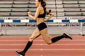 female athlete running sprint on stadium track