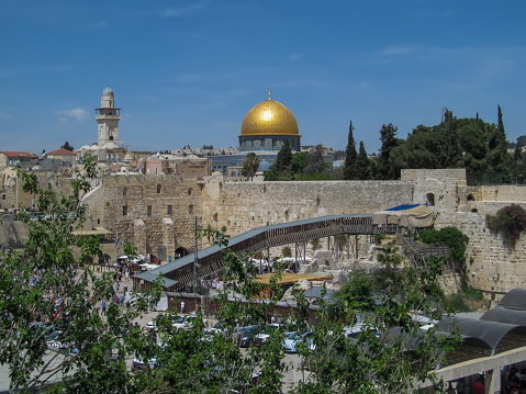 Jerusalem, Israel - April 24. 2014:  Unidentified tourists visit Western Wall. Dome of the Rock on the Temple Mount on in the old city of Jerusalem. The Temple Mount - and the golden Dome