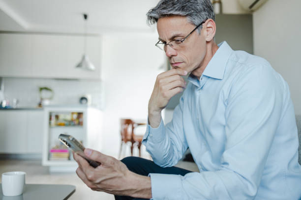 istock Uncertain mature man using smart phone at home 1468585097