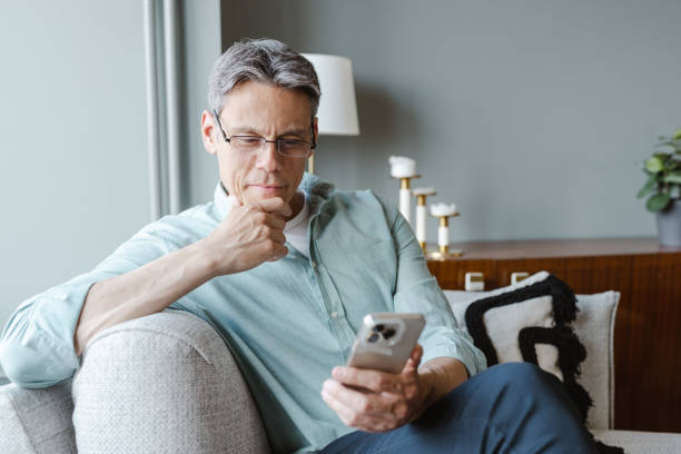 istock Uncertain mature man using smart phone at home 1468585613