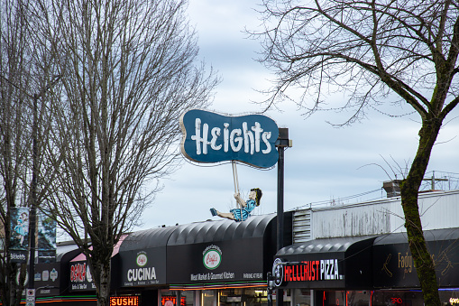 Burnaby, CANADA - Jan 15 2023 : Helen's The Heights Swinging Girl, an iconic and historic neon sign at Burnaby Heights designed by Reeve Lehman, seen in cloudy day. original was unveiled in 1957