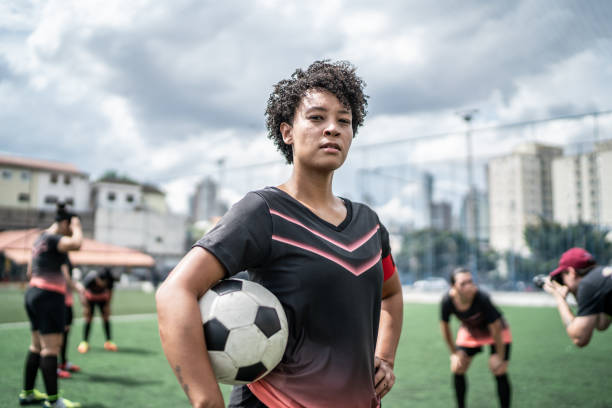 ritratto di una giocatrice di calcio femminile che tiene un pallone da calcio nel campo - sports uniform immagine foto e immagini stock