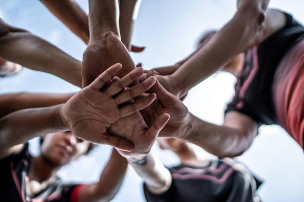 gros plan d’une équipe féminine de soccer empilant les mains sur le terrain - équipe sportive photos et images de collection