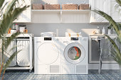 Laundry Room Interior With Washing Machine, Dryer, White Cabinets, Drying Rack And Blurred Plants